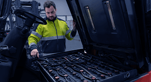 Technicien réalisant l'entretien d'une batterie de chariot élévateur dans un entrepôt